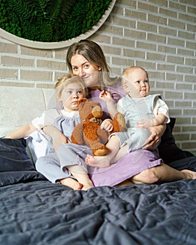 Happy mother with two kids relaxing on big bed at home