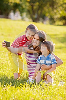 Happy mother with two kids, taking pictures in the park