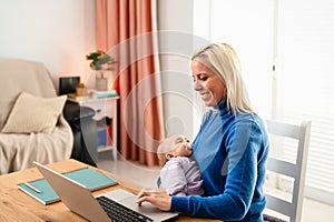 Happy mother using laptop while small baby is sleeping