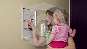 Happy mother woman with little daughter girl turn on lever in fuse box
