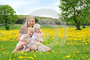 Happy Mother and Young Children Relaxing in Flower Meadow