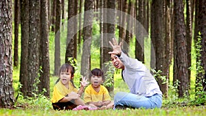 Happy mother and youngest daughter playing in green lawn in the park while the eldest daughter sat next to with sadness. Concept o