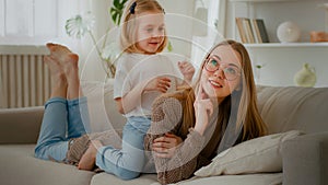 Happy motherhood family bonding affectionate love Caucasian mother lying on couch sofa daughter little girl child