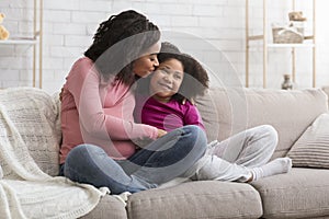 Happy Motherhood. Loving Pregnant Black Mom Kissing Little Daughter At Home