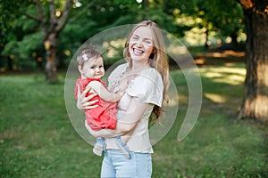 Happy motherhood. Middle age smiling Caucasian mother and girl toddler daughter hugging in park. Mom embracing child baby on