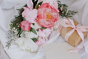 Happy Mothers day. Beautiful peonies bouquet, greeting card, gift on soft white fabric on chair