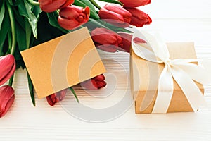 Happy Mothers day. Beautiful red tulips with gift box and craft card with space for text on white wooden background. Pink tulips