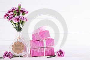 Happy mothers day concept. Gift box with pink carnation flower on white wooden table background