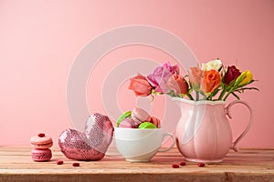 Happy Mothers day concept with macaroons french cookies and rose flower bouquet on wooden table over pink background