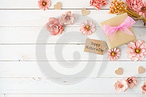 Happy Mothers Day corner border with paper flowers, gift box and tag over a white wood background