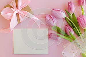 Happy Mothers day. Empty greeting card, pink tulips bouquet and gift box flat lay on pink background. Greeting card template with