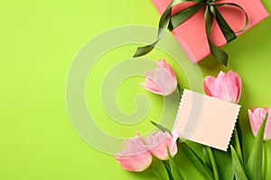 Happy Mothers Day gift with ribbon bow, greeting card template, and tulips on green background. Flat lay, top view, copy space