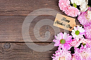 Happy Mothers Day gift tag with side border of flowers over a dark wood background