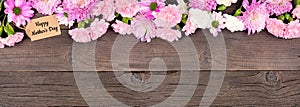 Happy Mothers Day gift tag with top border of flowers over a dark wood banner background