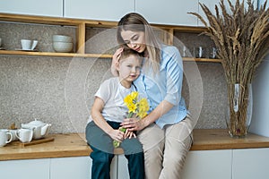 Happy mothers day! little son gives flowers to mom, boy congratulates mom, flowers in the hands of a boy, yellow daffodils, happy