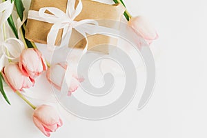 Happy Mothers day. Pink tulips flat lay with ribbon and gift box on white background, space for text. Stylish soft image. Happy