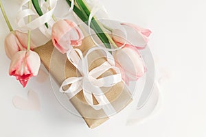 Happy Mothers day. Pink tulips flat lay with ribbon and gift box on white background. Stylish soft image of spring flowers. Happy