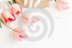 Happy Mothers day.  Pink tulips with ribbon and gift box on white background, space for text. Stylish soft image of spring flowers