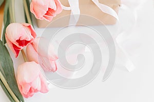 Happy Mothers day. Pink tulips with ribbon on white background with gift box. Stylish tender image. Happy womens day. Greeting