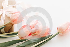 Happy Mothers day. Pink tulips with ribbon on white background with gift box. Stylish tender image. Happy womens day. Greeting