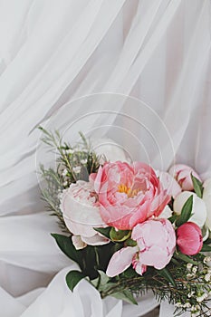 Happy Mothers day. Stylish peonies bouquet on soft white fabric on rustic chair. Space for text