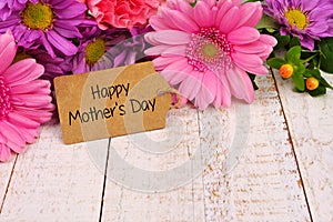 Happy Mothers Day tag close up with flowers over white wood