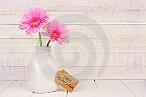 Happy Mothers Day tag with pink flowers against white wood