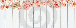 Happy Mothers Day top border with pink paper flowers and gift tag over a white wood banner background