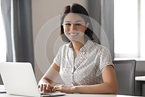 Happy motivated asian female employee working with computer portrait.