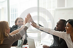 Happy motivated diverse business team giving high five at meetin