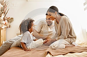 Happy multi ethnic family mom, dad and child  laughing, playing and tickles   in bed   at home
