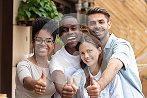 Happy multi-ethnic friends group showing thumbs up looking at camera