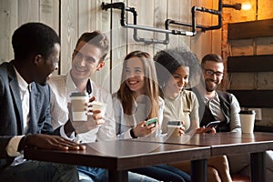 Happy multi-ethnic group of friends talking using smartphones at