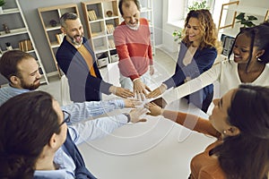 Happy multi-ethnic people group join helping hands in circle together in office
