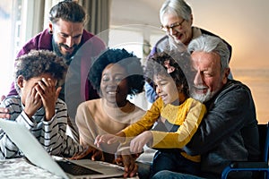 Happy multi-generation family gathering around notebbok and having fun during a video call