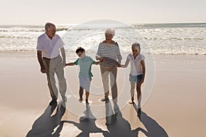 Happy multi-generation family holding hands and standing on beach