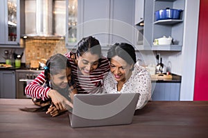 Happy multi-generation family using laptop in kitchen