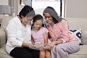 Happy multi-generation family using mobile phone together at home