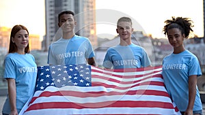 Happy multi-racial volunteers holding American flag, charity foundation, help