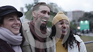 Happy multicultural friends laughing together outdoors in city street in winter