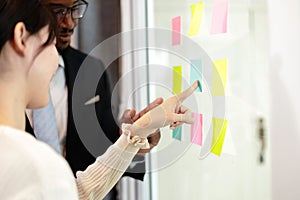 Happy multiethnic business team meeting pointing at post it notes on glass board. business team meeting brainstorm share idea at