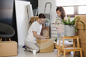 Happy multiethnic couple just moved into new empty apartment unpacking