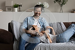 Happy multiethnic couple relax on couch hugging