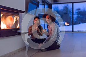 Happy multiethnic couple sitting in front of fireplace
