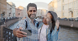 Happy multiethnic couple of tourists taking selfie in old city