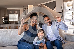 Happy multiethnic family with child holding cardboard roof