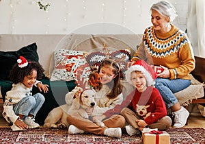 Happy multiethnic family, grandmother with grandchildren and dog enjoying Christmas day