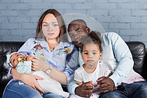Happy multiethnic family sitting on the sofa in modern interior