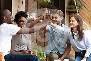 Happy multiethnic friends giving high five, celebrate success photo