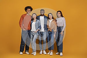 Happy multiethnic group standing together on orange background